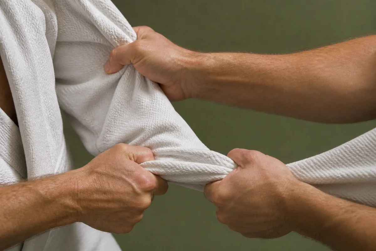 Mains d&rsquo;un judoka serrant le revers et la manche d&rsquo;un judogi blanc pendant un kumi-kata